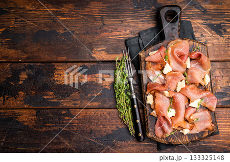Italian Prosciutto parma ham with herbs and parmesan cheese on wooden board. wooden background. top view 133325148