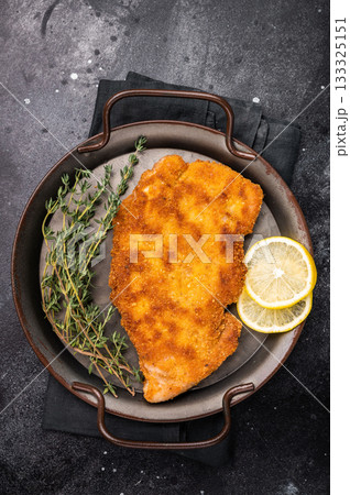German Wiener schnitzel steak, breaded pork fillet meat. black background. top view German Wiener schnitzel steak, breaded pork fillet meat. black background. top view 133325151