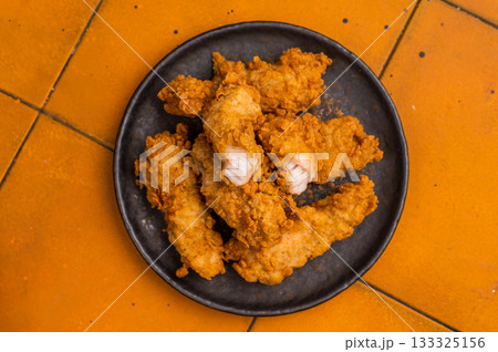 Chicken tenders, deep fried strips from breast fillet. orange background. top view Chicken tenders, deep fried strips from breast fillet. orange background. top view 133325156