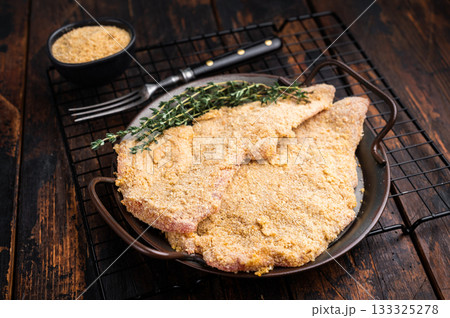 Viennese breaded raw Schnitzel steak on a tray. wooden background. top view 133325278