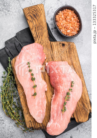 Ready for cooking pork loin fillets, raw tenderloin meat on a wooden board. Gray background. top view 133325317