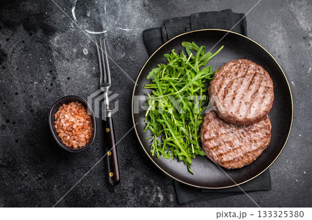 Grilled beef and pork meat patty paired with fresh veggies, an essential component for gourmet burgers. black background. top view 133325380