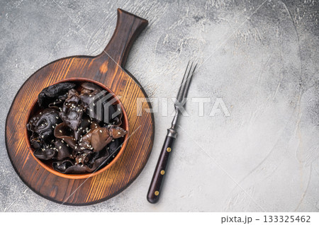 Organic wood ear mushrooms on a wooden cutting board, showcasing their unique shape and rich culinary potential. white background. top view Organic wood ear mushrooms on a wooden cutting board, showcasing their unique shape and rich culinary potential. white background. top view 133325462
