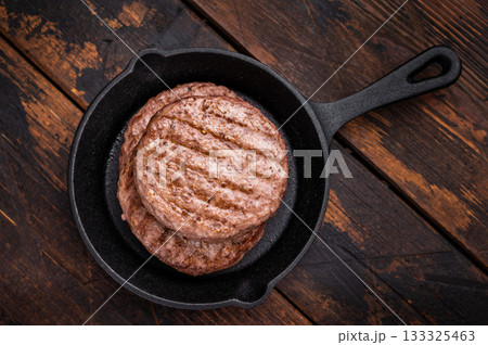 Deliciously charred grilled meat burger patty on the grill, perfect for satisfying cravings at any cookout. wooden background. top view Deliciously charred grilled meat burger patty on the grill, perfect for satisfying cravings at any cookout. wooden background. top view 133325463