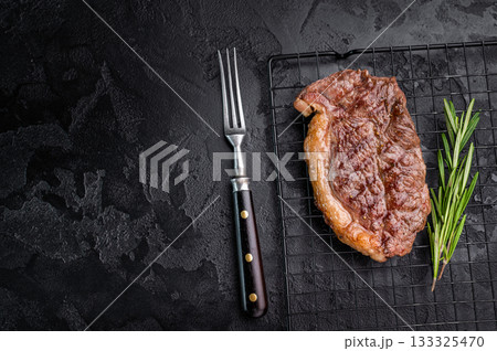 Juicy grilled striploin New York steak with perfect grill marks, ideal for a hearty meal or summer barbecue. black background. top view Juicy grilled striploin New York steak with perfect grill marks, ideal for a hearty meal or summer barbecue. black background. top view 133325470