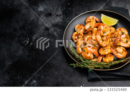 Grilled spicy Shrimps Prawns with garlic and lime in a plate. Black background. Top view 133325480
