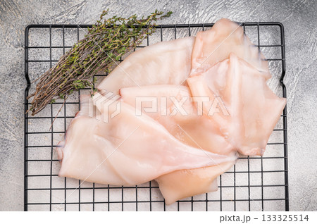 Close up of tender raw squid showcasing its smooth texture, ideal for culinary creativity and seafood lovers. grey background. top view 133325514