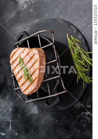 Juicy grilled tuna steak, perfectly seared with a smoky flavor, ideal for seafood lovers and gourmet dishes. black background. top view 133325515