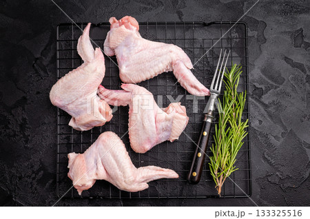 Uncooked chicken wings, showcasing their tender meat, ideal for flavorful recipes and delicious appetizers. black background. top view 133325516