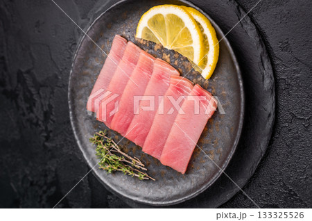 Vibrant tuna sashimi arranged on a plate, showcasing its rich color and delicate texture for an exquisite meal. black background. top view 133325526