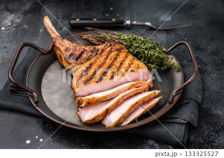 Flavorful grilled pork loin chop with bone, expertly cooked to perfection, making it the star of any meal. black background. top view 133325527