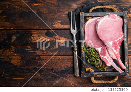 Uncooked Tomahawk pork chop steak, ready to be seasoned and cooked to perfection for a mouthwatering meal. wooden background. top view 133325569