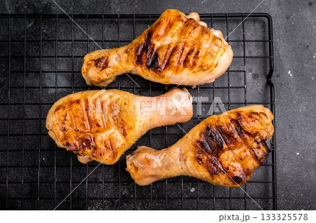 Savory BBQ chicken legs, drumsticks beautifully caramelized on the grill, ready to be enjoyed with your favorite dipping sauce. black background. top view Savory BBQ chicken legs, drumsticks beautifully caramelized on the grill, ready to be enjoyed with your favorite dipping sauce. black background. top view 133325578