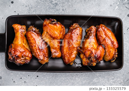 Juicy barbecue chicken wings, perfectly grilled and glazed, ideal for your next summer cookout or party. grey background. top view Juicy barbecue chicken wings, perfectly grilled and glazed, ideal for your next summer cookout or party. grey background. top view 133325579