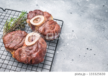 Tender veal osso buco, cross cut shank simmered in rich sauce, a timeless recipe that delights the senses and warms the heart. grey background. top view 133325630