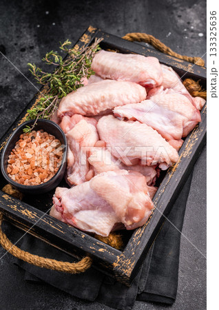 Beautifully arranged raw chicken wings, ready to soak up your favorite marinades for a tasty culinary adventure. black background. top view Beautifully arranged raw chicken wings, ready to soak up your favorite marinades for a tasty culinary adventure. black background. top view 133325636