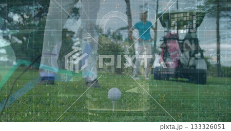 Addressing golfer lining up golf ball on tee with club on fairway, golf cart with bags 133326051
