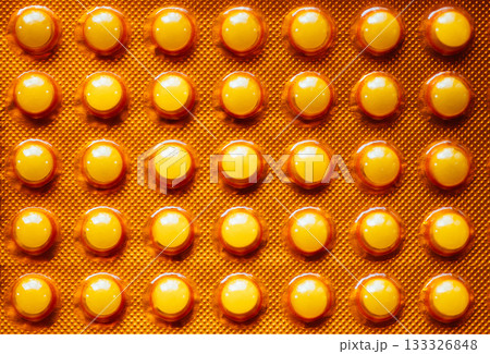 Closeup blister pack with round softgel pills creating a sterile repeating pattern. Safe pharmacy background for healthcare packaging and research uses. 133326848