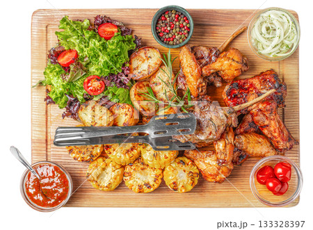 Grilled meat assortment with roasted vegetables, fresh salad, corn, sauces, and spices served on wooden board, top view rustic food composition ideal for restaurant advertising 133328397