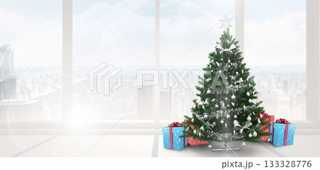 Christmas tree is standing beside high-rise windows with silver tinsel, star topper and presents 133328776