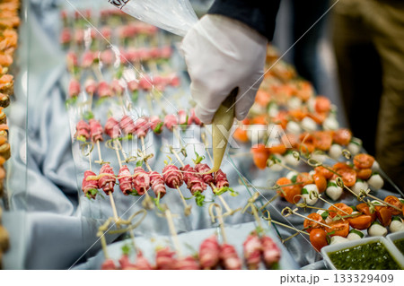 Chef garnishing delicious appetizers for wedding reception buffet Chef garnishing delicious appetizers for wedding reception buffet 133329409