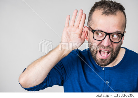 Man eavesdropping with hand close to ear 133330206