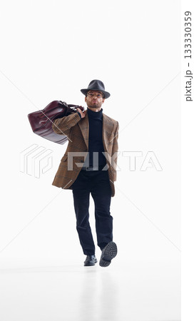 Confident businessman walking with large travel bag in classic outfit 133330359