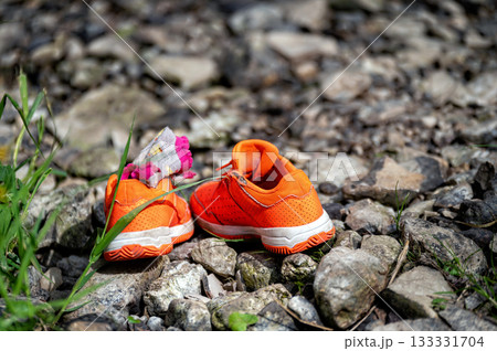 orange children's sneakers on a rocky surface, close-up 133331704