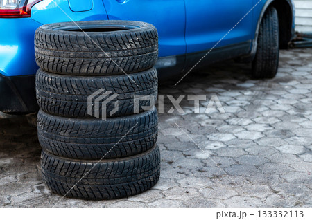 a set of winter tires next to the car in the wheel service, the concept of seasonal tire change 133332113