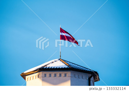 Latvian Flag on the flagpole fluttering in the wind against blue clear sky, copy space 133332114