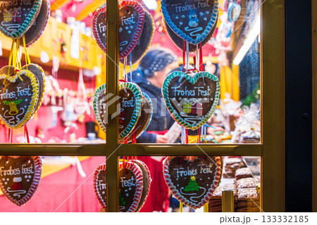 Wuerzburg, Germany, December 22th, 2024. A festive christmas market stall viewed through a window, decorated with hanging gingerbread heart cookies with colorful icing messages. 133332185