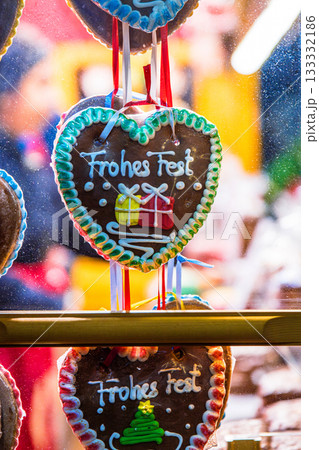 A holiday market stall packed with Frohes Fest - Happy Holidays - gingerbread hearts in a market stall window at Christmas market. Shot through the glass A holiday market stall packed with Frohes Fest - Happy Holidays - gingerbread hearts in a market stall window at Christmas market. Shot through the glass 133332186