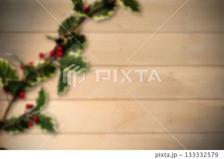 Holly branch is featuring green leaves, red berries over light plank in flat style, copy space 133332579