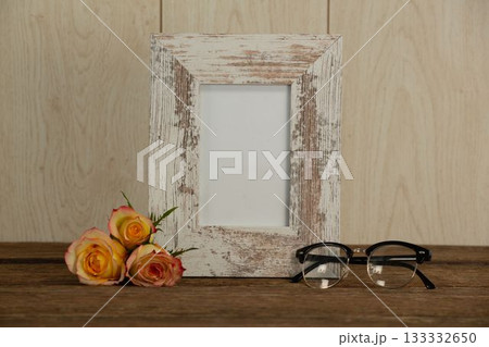 Photo frame, spectacle and flowers on table 133332650