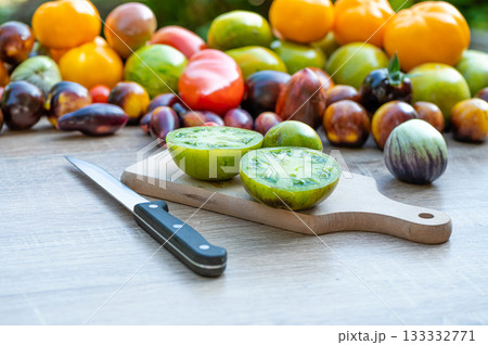 table with a cutting board with sliced tomatoes with different colored tomatoes in the background 133332771
