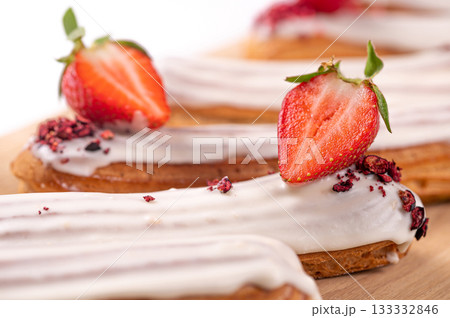 delicious eclair with icing and whipped cream filling, French dessert with strawberries, closeup delicious eclair with icing and whipped cream filling, French dessert with strawberries, closeup 133332846