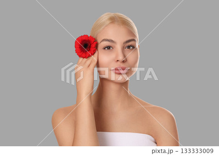 Model showcases skincare with a bright flower accessory 133333009