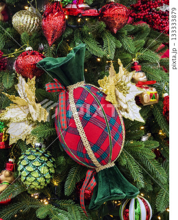 Colorful decorative ornament resembling candy on a Christmas tree filled with festive decorations and lights Colorful decorative ornament resembling candy on a Christmas tree filled with festive decorations and lights 133333879