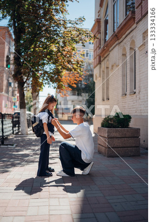 Father adjusts daughter backpack on a sunny day in the city Father adjusts daughter backpack on a sunny day in the city 133334166
