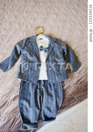 Cute baby suit hanging on a wall hook in a soft setting Cute baby suit hanging on a wall hook in a soft setting 133334216