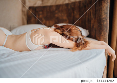 Woman relaxing on bed in casual attire during afternoon light in cozy room 133334262
