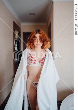 Young woman wearing floral lingerie and a white towel in hotel hallway Young woman wearing floral lingerie and a white towel in hotel hallway 133334291