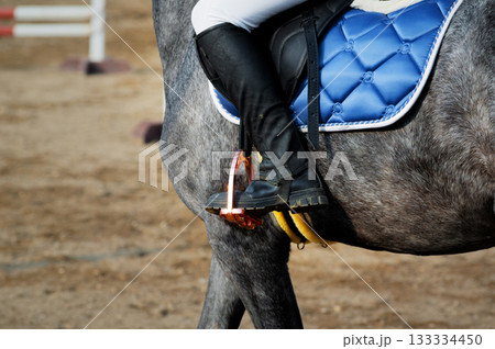 Women's black leather jockey boot in stirrup while sitting on a horse at a paddock walk 133334450