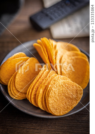 Crispy potato chips on plate on wooden table. Crispy potato chips on plate on wooden table. 133335864