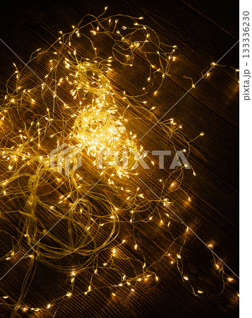 Garland of yellow LEDs on a brown wooden background. Garland of yellow LEDs on a brown wooden background. 133336230