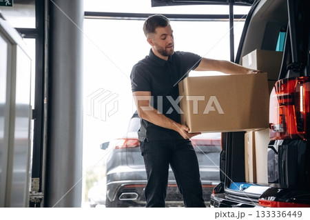 Delivery man or loader is near the car with a box 133336449