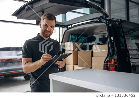 Data in the notepad. Delivery man or loader is near the car with a box Data in the notepad. Delivery man or loader is near the car with a box 133336452