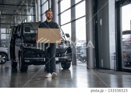 Smiling, positive facial expression. Delivery man or loader is near the car with a box 133336525