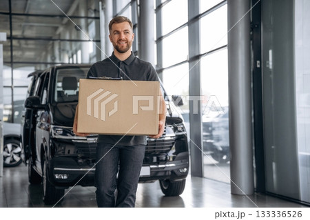 Smiling, positive facial expression. Delivery man or loader is near the car with a box 133336526
