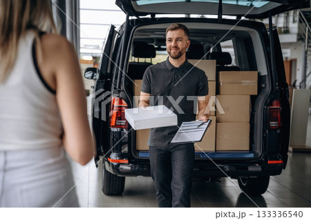 Customer is taking her order. Woman is with delivery man, with the car Customer is taking her order. Woman is with delivery man, with the car 133336540